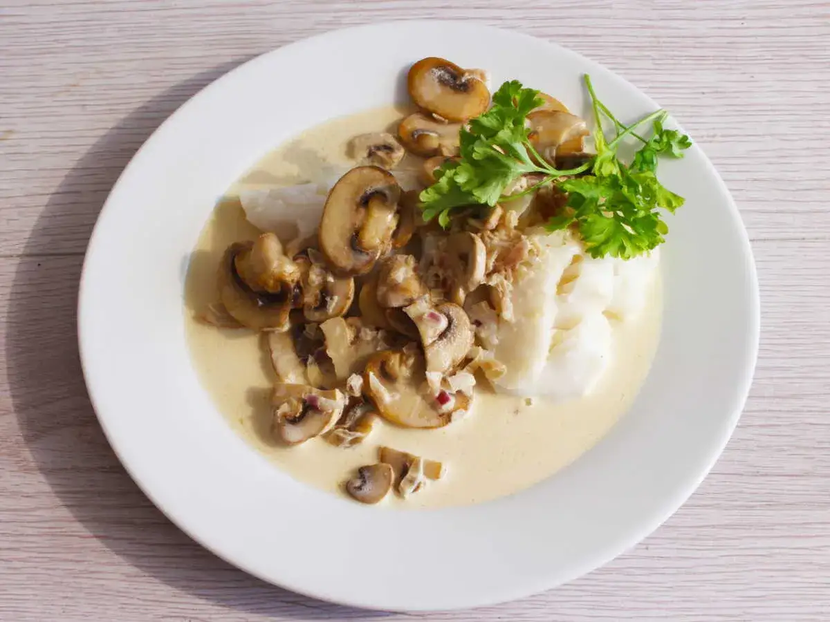 Poisson blanc nappé d'une onctueuse sauce normande aux champignons, garni de persil frais. Un délice !