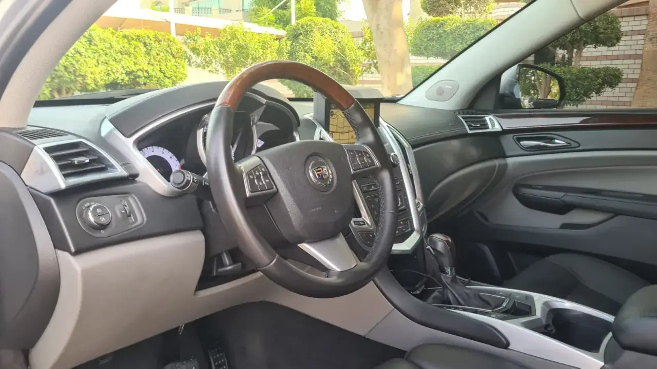 Wnętrze Cadillaca SRX z drewnianą kierownicą i ekranem nawigacji.