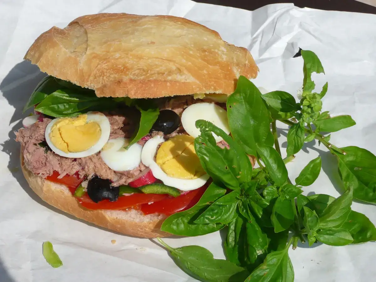 Un généreux pan bagnat garni de thon, œufs durs, olives, tomates et basilic frais.