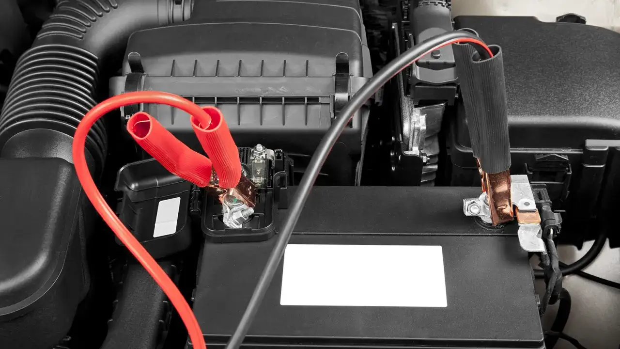 Pinzas rojas conectadas a la batería para arrancar coche. Cables de arranque en el compartimento del motor.