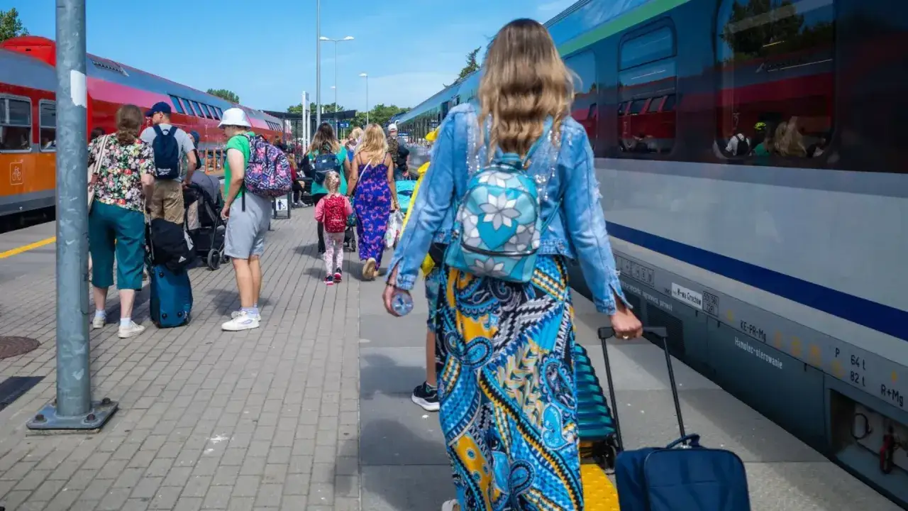 Rodzina z bagażami na peronie, gotowa do podróży. Taniej z bliskimi to świetny sposób na wspólne wakacje.