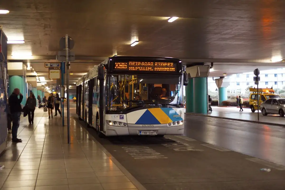 Autobus in sosta al porto di Atene, con passeggeri in attesa sulla banchina.