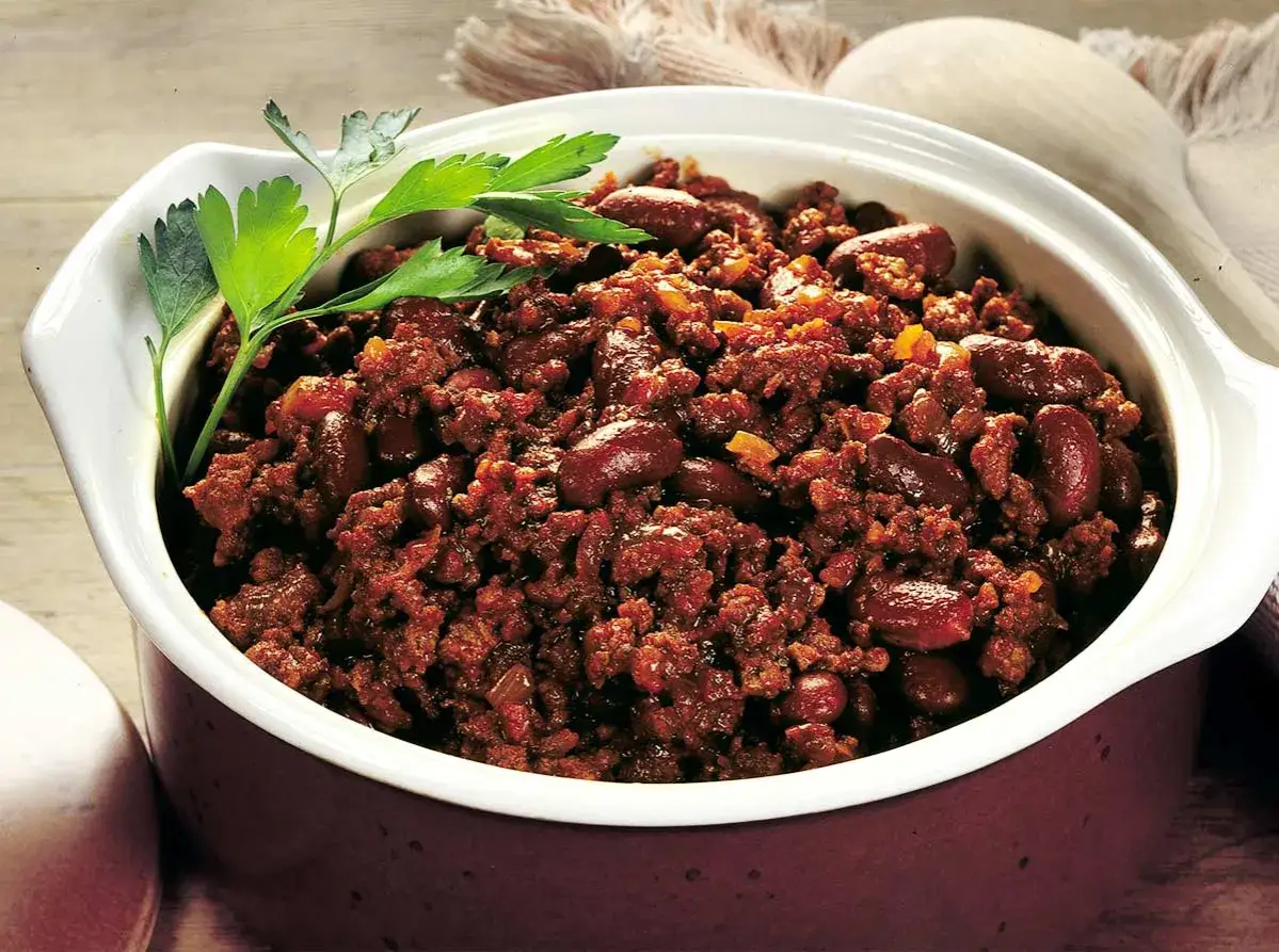 En skål med mustig texas chili med bönor och köttfärs, garnerad med persilja.