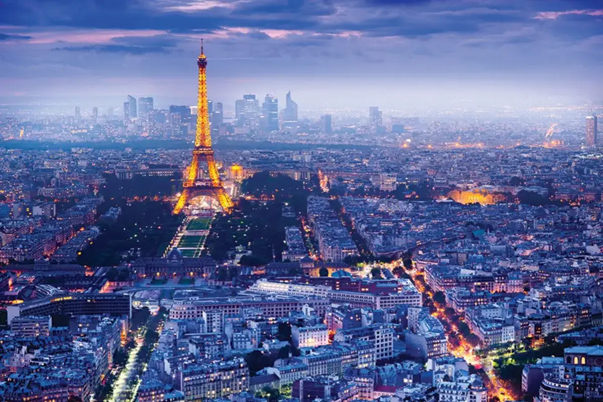 Wieczorny Paryż z rozświetloną wieżą Eiffel. Miasto tętni życiem, a światła budynków tworzą magiczny krajobraz.