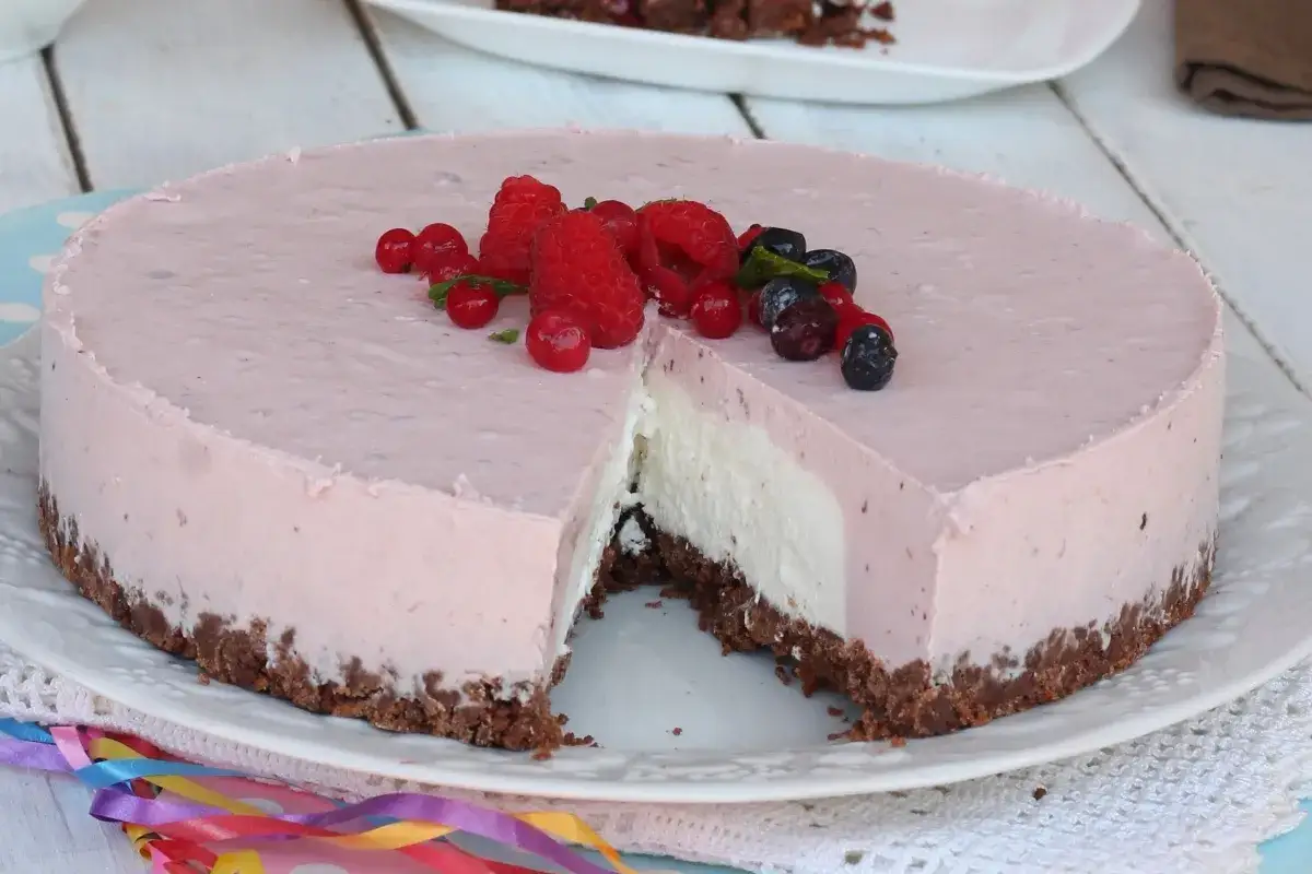 Deliziosa torta fredda allo yogurt con base croccante, decorata con frutti di bosco freschi. Perfetta per ogni occasione.