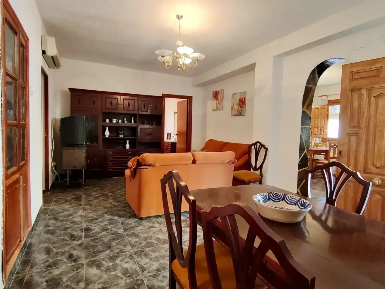Sal&oacute;n con muebles de madera oscura, sof&aacute;s naranjas y mesa de comedor. Las **gradual homes opiniones** sobre este espacio sugieren un ambiente acogedor.
