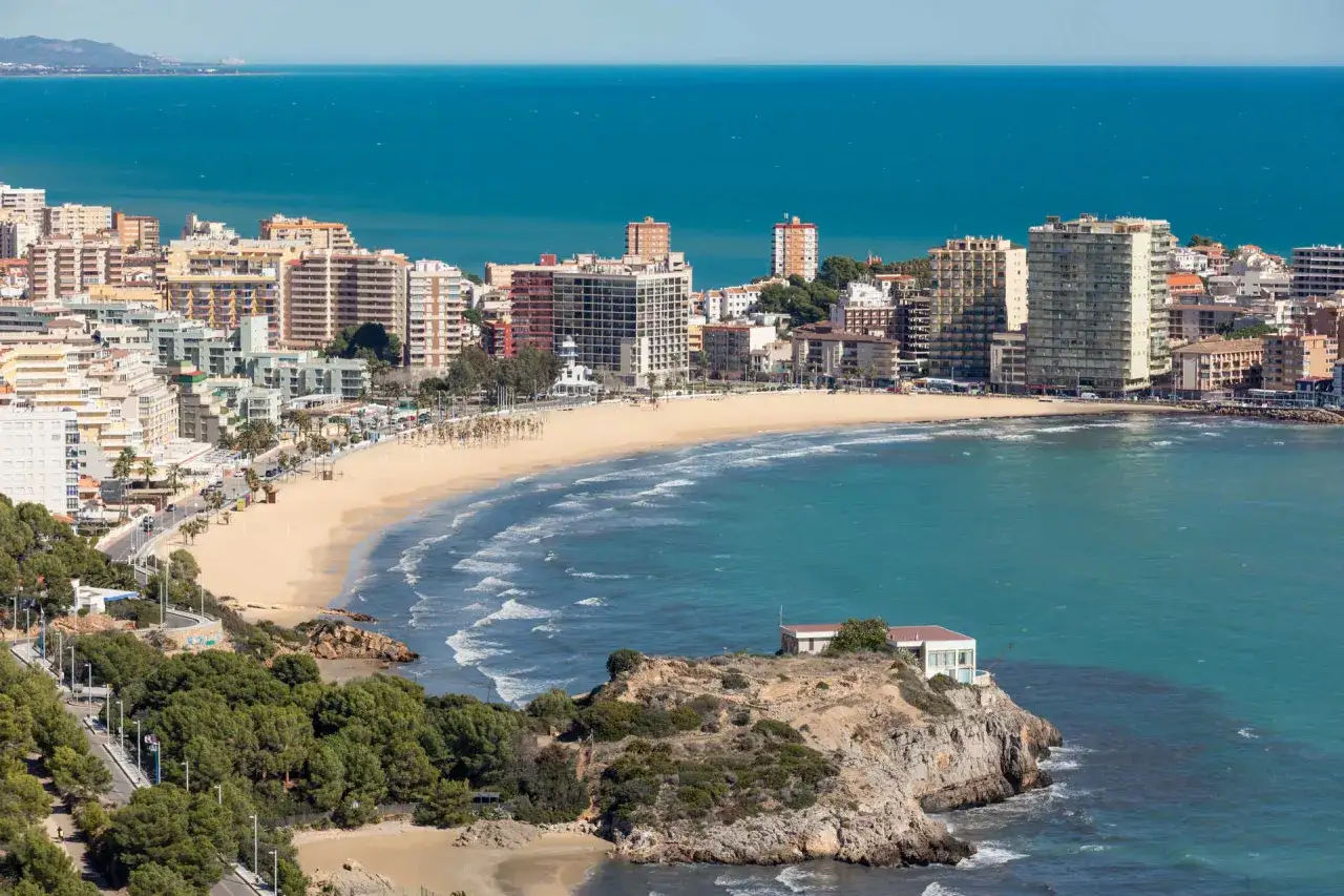 Vista panorámica de la playa de la Concha en Oropesa del Mar, con edificios residenciales y el mar Mediterráneo azul.