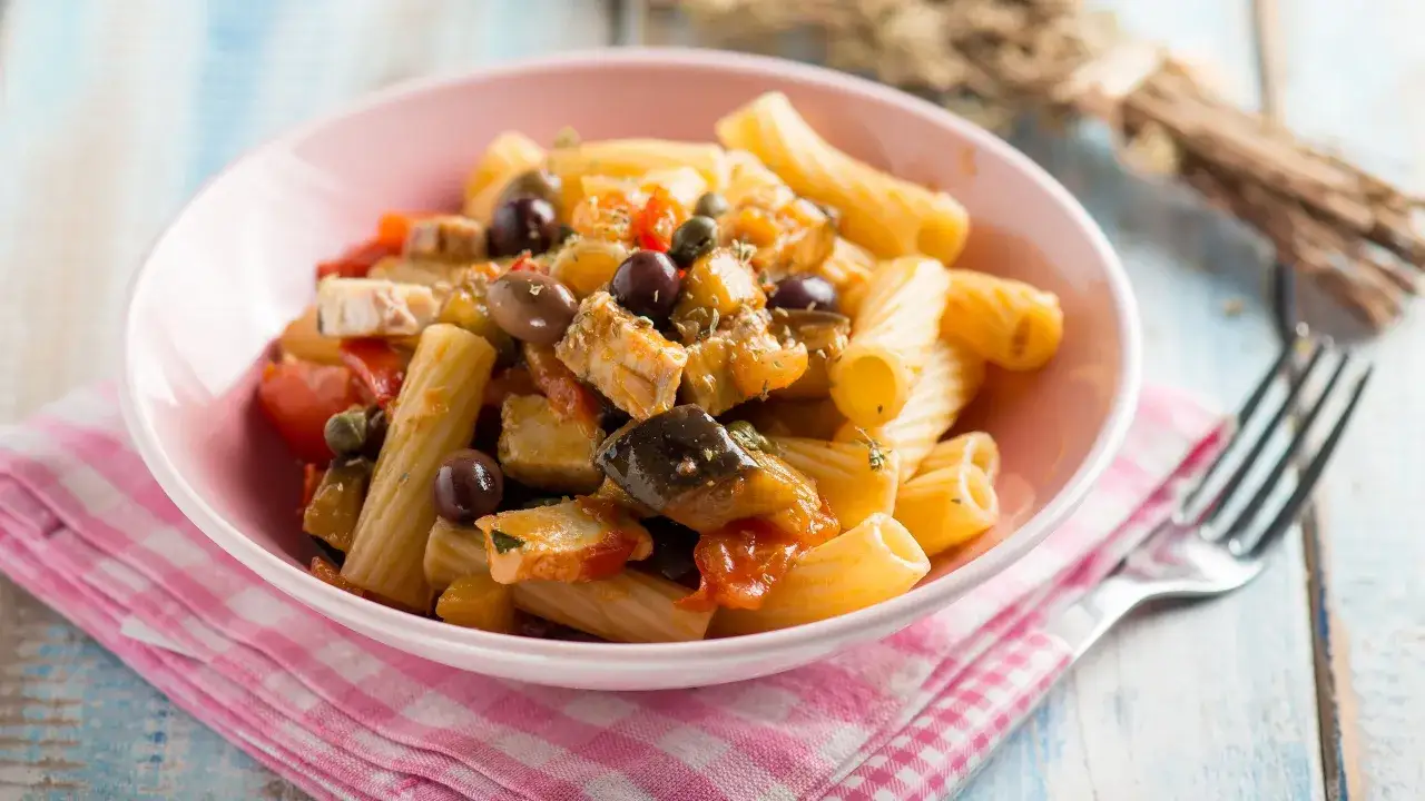 Piatto di pasta con pesce spada, melanzane, pomodorini e olive nere. Un classico sapore mediterraneo.