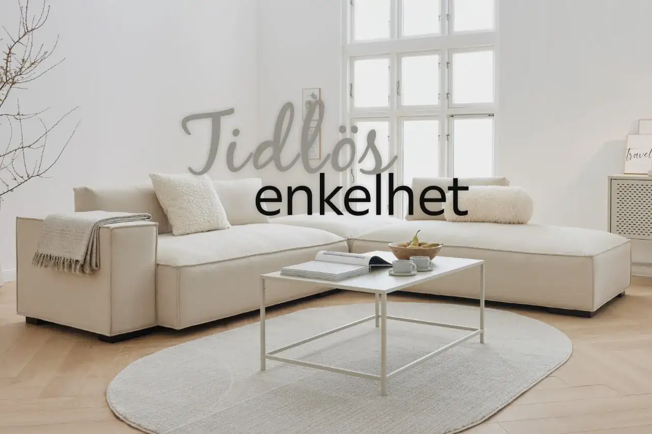 En ljus soffa med kuddar och pl&auml;d ger soffa inspiration. Ett vitt soffbord med b&ouml;cker och fruktsk&aring;l.