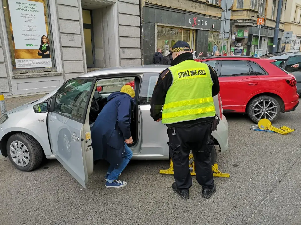 Strażnik miejski interweniuje przy samochodzie na terenie wspólnoty mieszkaniowej. Zastosowano blokadę na koło.