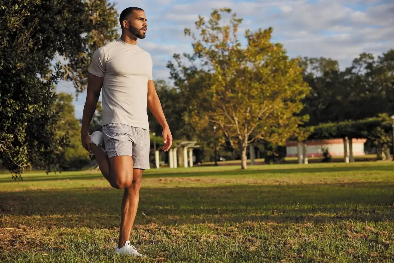 Uomo si allunga in un parco, pronto per la corsa running.