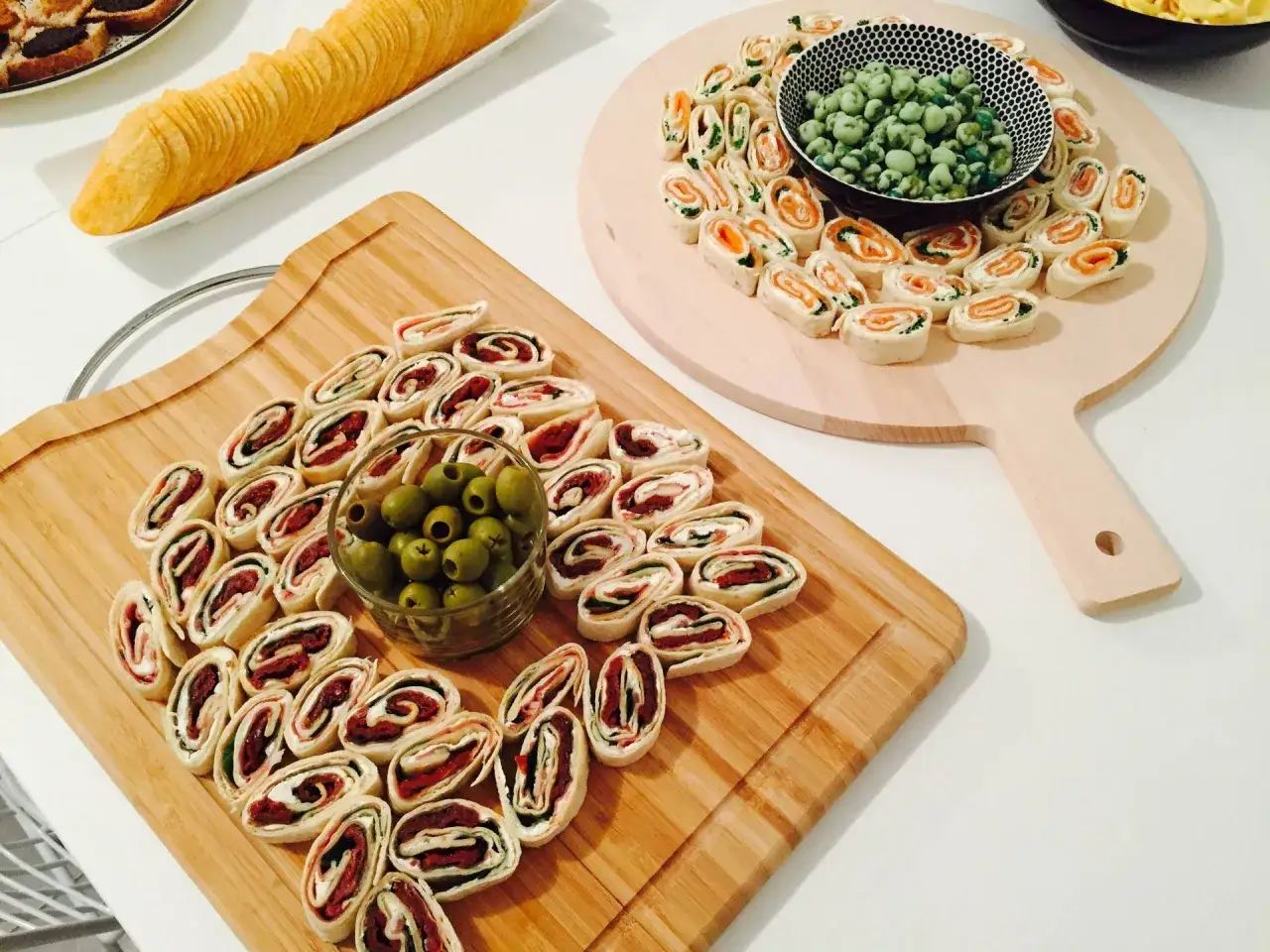 Délicieux wrap apéro enroulés sur une planche en bois, accompagnés d'olives vertes. Parfait pour un moment convivial.