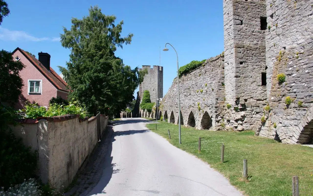 Droga w Visby prowadzi obok zabytkowych murów obronnych i różowego domu.
