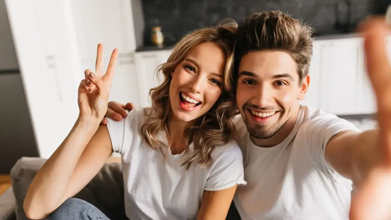 Uśmiechnięta para robi selfie, zastanawiamy się, dlaczego popularna para usunęła wspólne zdjęcia z mediów społecznościowych.