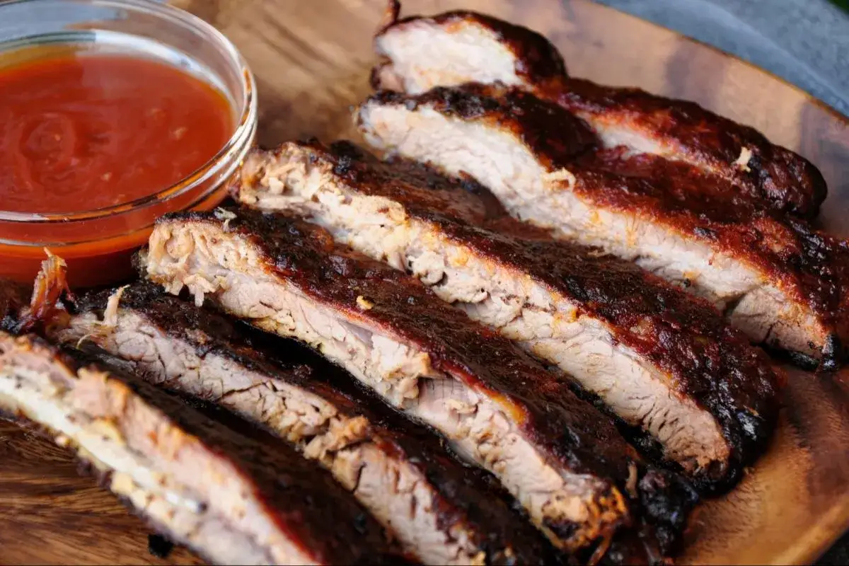Délicieux ribs de porc caramélisés, prêts pour la cuisson. Une sauce barbecue onctueuse accompagne ce plat savoureux.