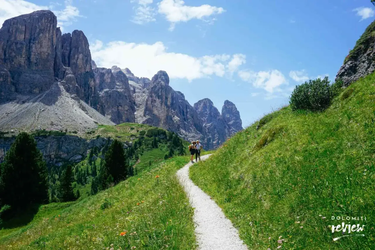 Sentiero in montagna, ideale per una vacanza in montagna estate. Due escursionisti ammirano le imponenti vette rocciose sotto un cielo azzurro.