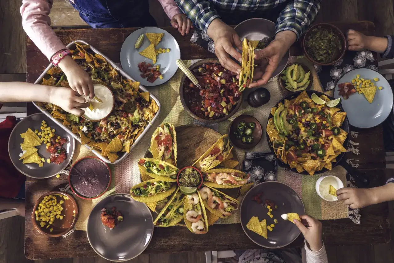 Familie isst Nachos und Tacos. Was sollte man in Mexiko nicht essen? Wahrscheinlich nichts von diesem k&ouml;stlichen Tisch!