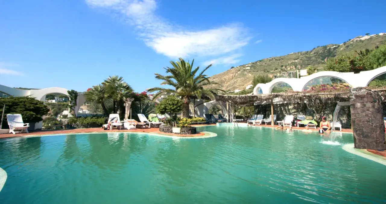 Piscina con lettini e palme, un'oasi di relax alle terme di Ischia.