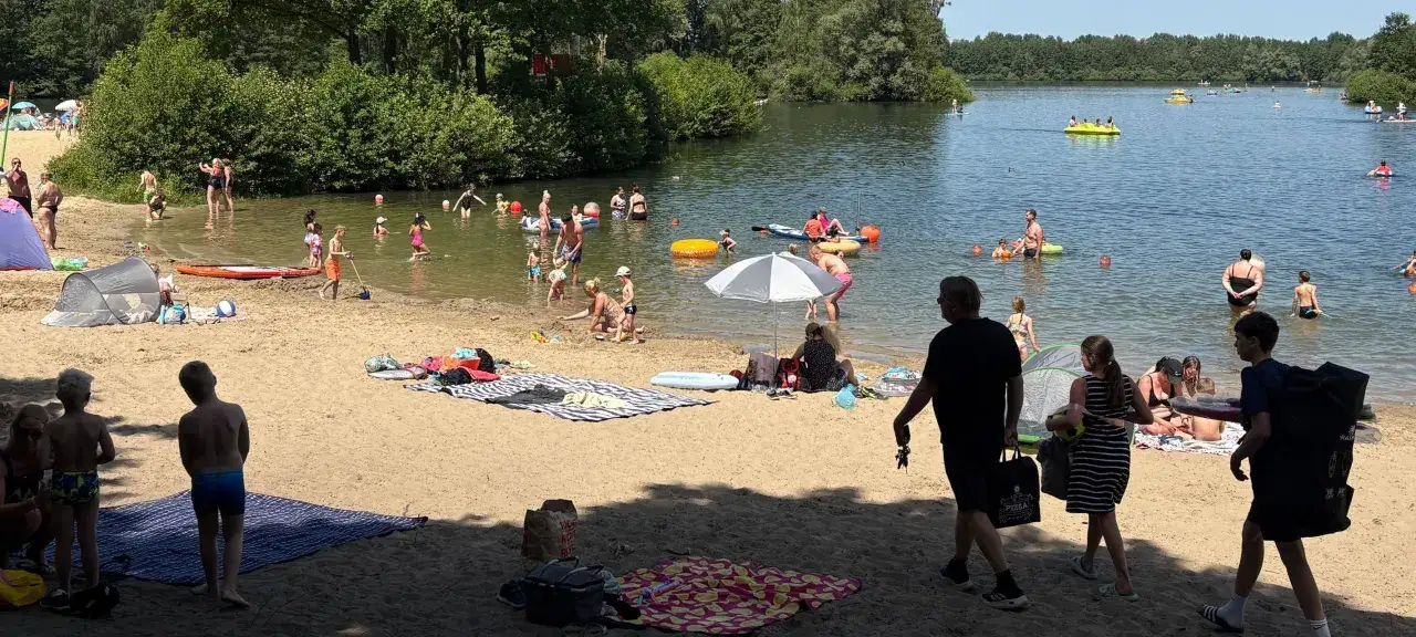 Menschen genie&szlig;en einen sonnigen Tag am lippstadt see. Kinder planschen im Wasser, w&auml;hrend andere am Strand entspannen.