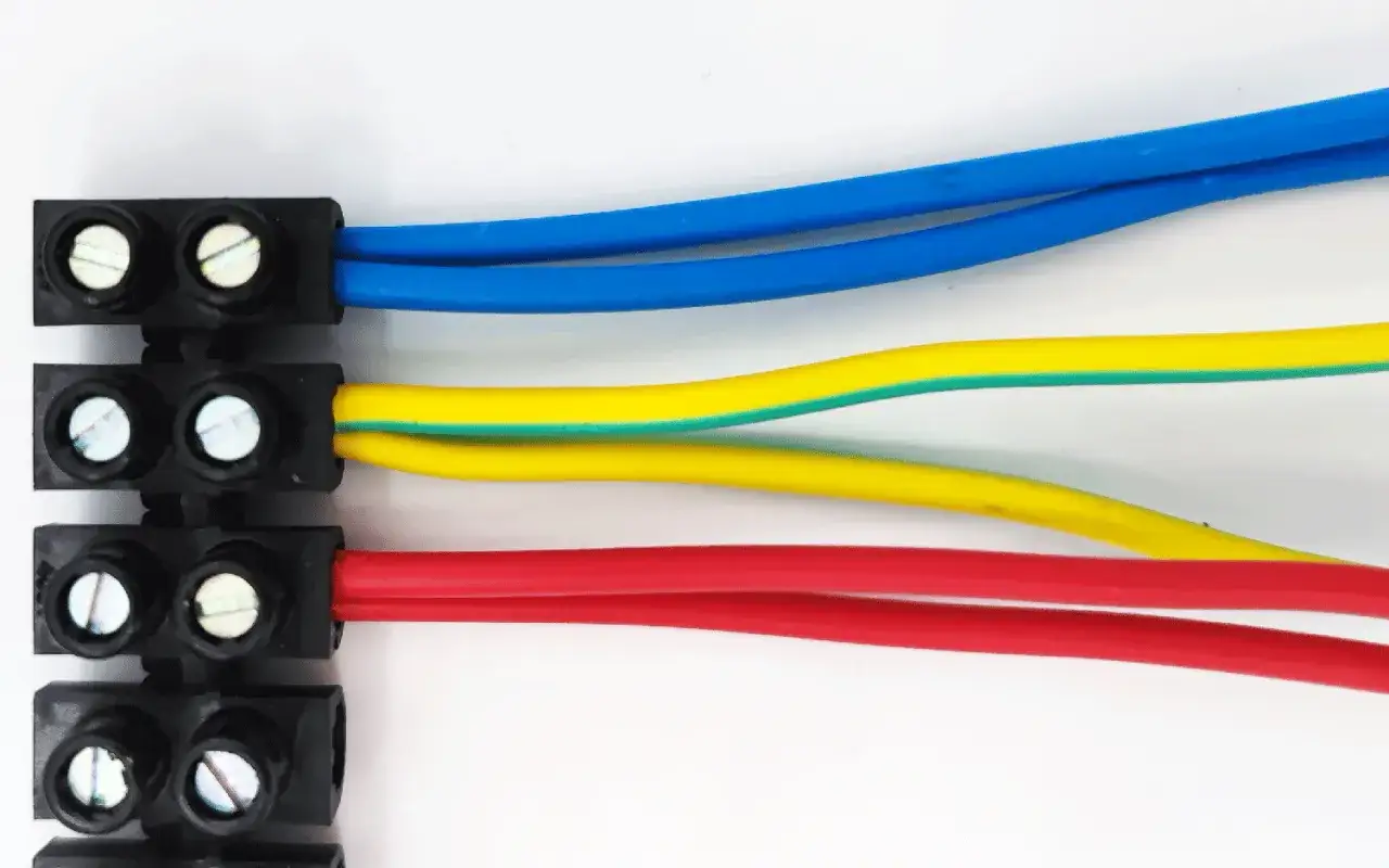 Trois fils électriques (bleu, jaune/vert, rouge) connectés à des dominos électriques. L'installation électrique est interdite sans précautions.