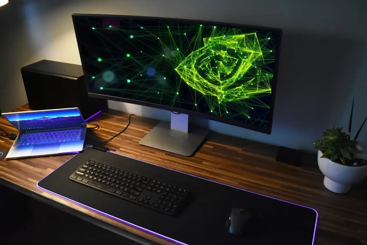 Stacja robocza z laptopem, monitorem i klawiaturą. Obok monitora stoi czarna obudowa, która może być kartą graficzną zewnętrzną do laptopa.