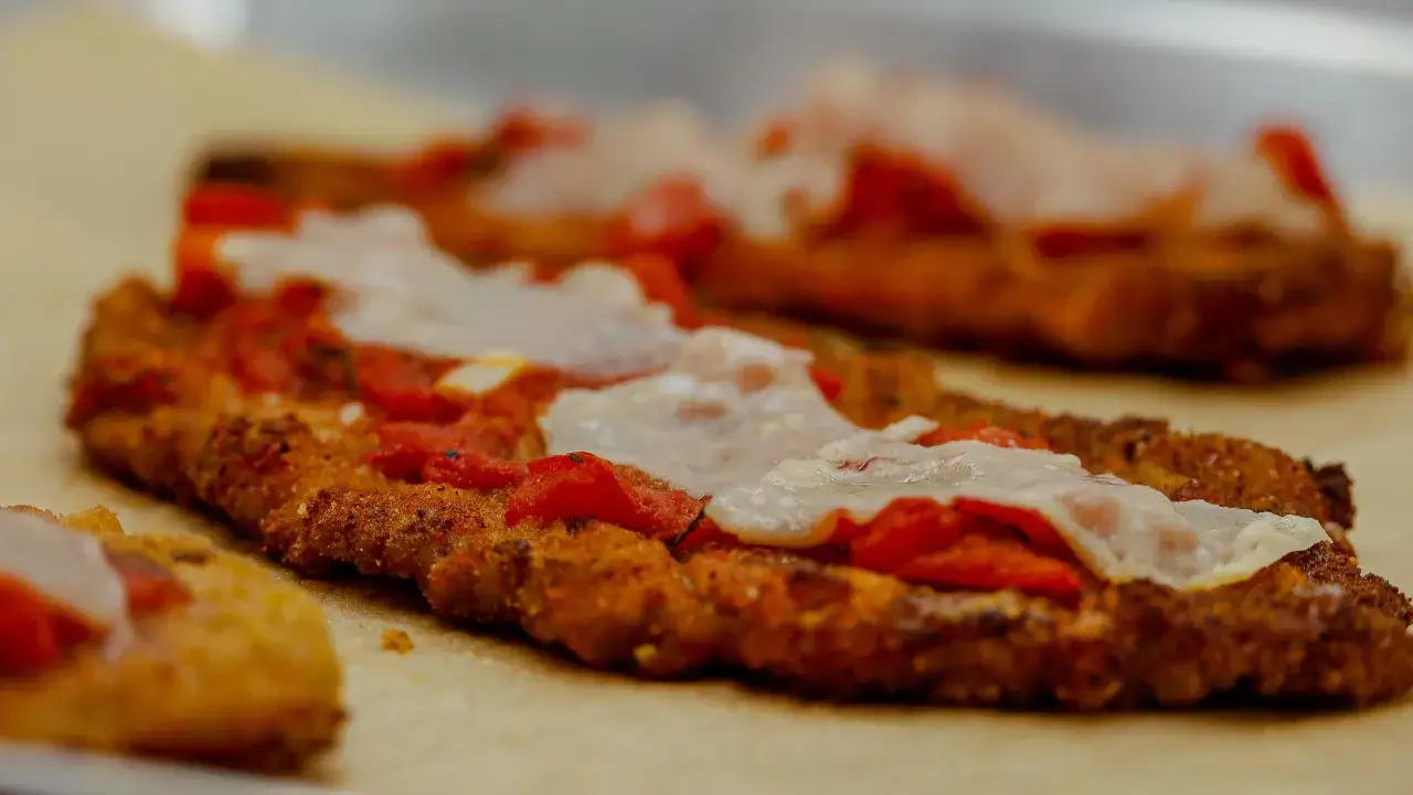 Escalopes de veau panées, garnies de sauce tomate et de mozzarella fondue, prêtes pour une délicieuse recette italienne parmigiana.