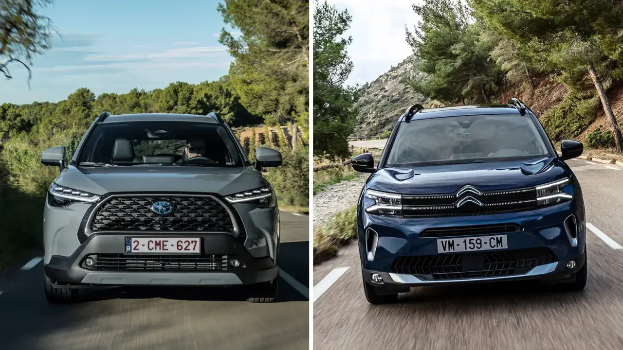 Szara nowa Corolla Cross i granatowy Citroën jadą drogą wśród drzew.