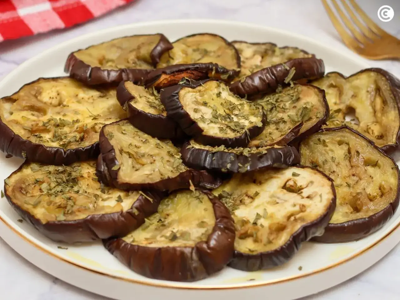 Rodajas de berenjena asada, sazonadas con hierbas, listas para servir como acompa&ntilde;amiento o base para un delicioso baba ganush.
