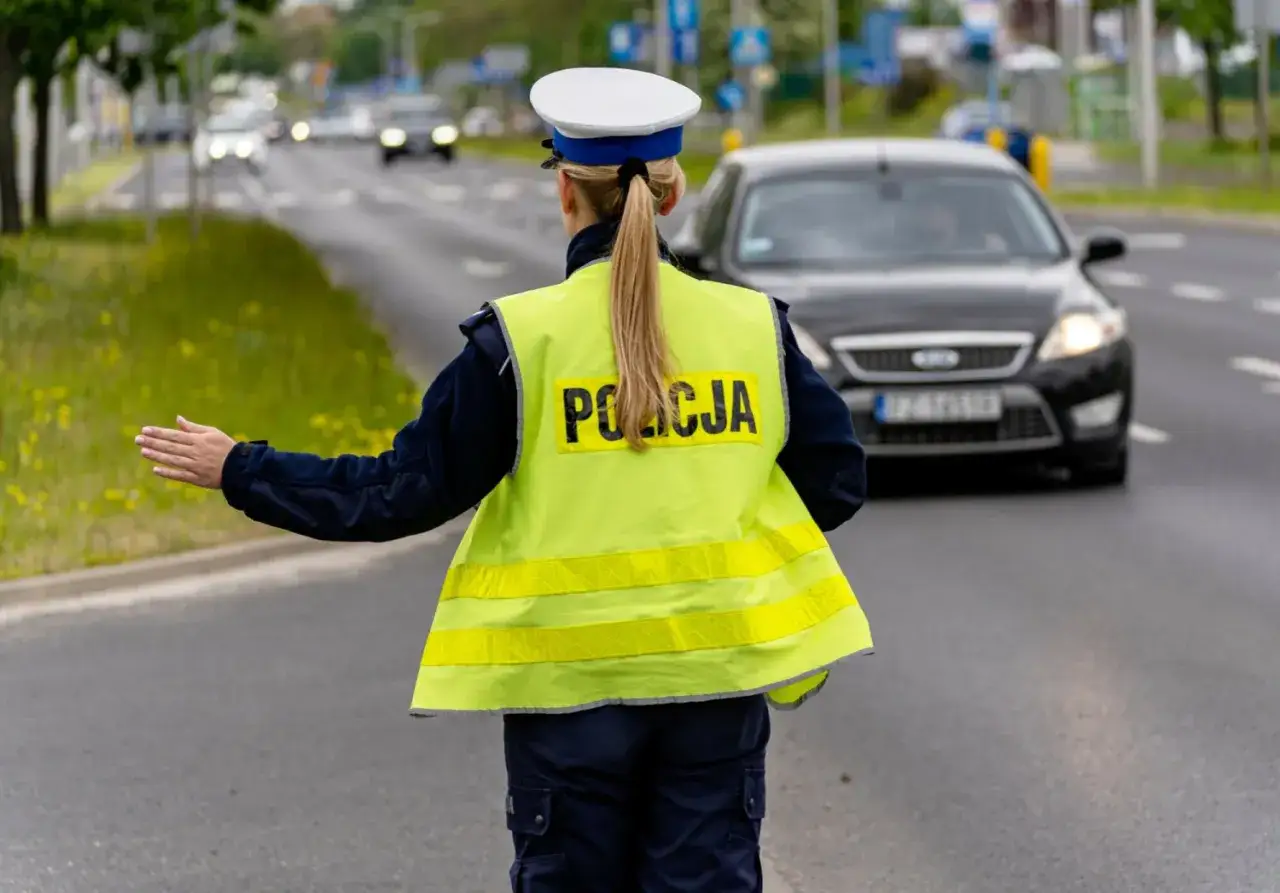 Policjantka kieruje ruchem, dbając o bezpieczne prowadzenie pojazdu przez kierowców na drodze.