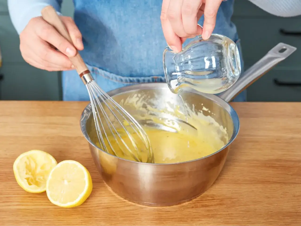 Zubereitung von Sauce Hollandaise: Ein Schneebesen rührt die cremige Sauce, während Zitronensaft hinzugefügt wird.