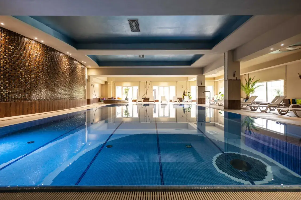 Wypoczynek w hotelu z basenem na Podlasiu. Błękitna woda, leżaki i relaksująca atmosfera.