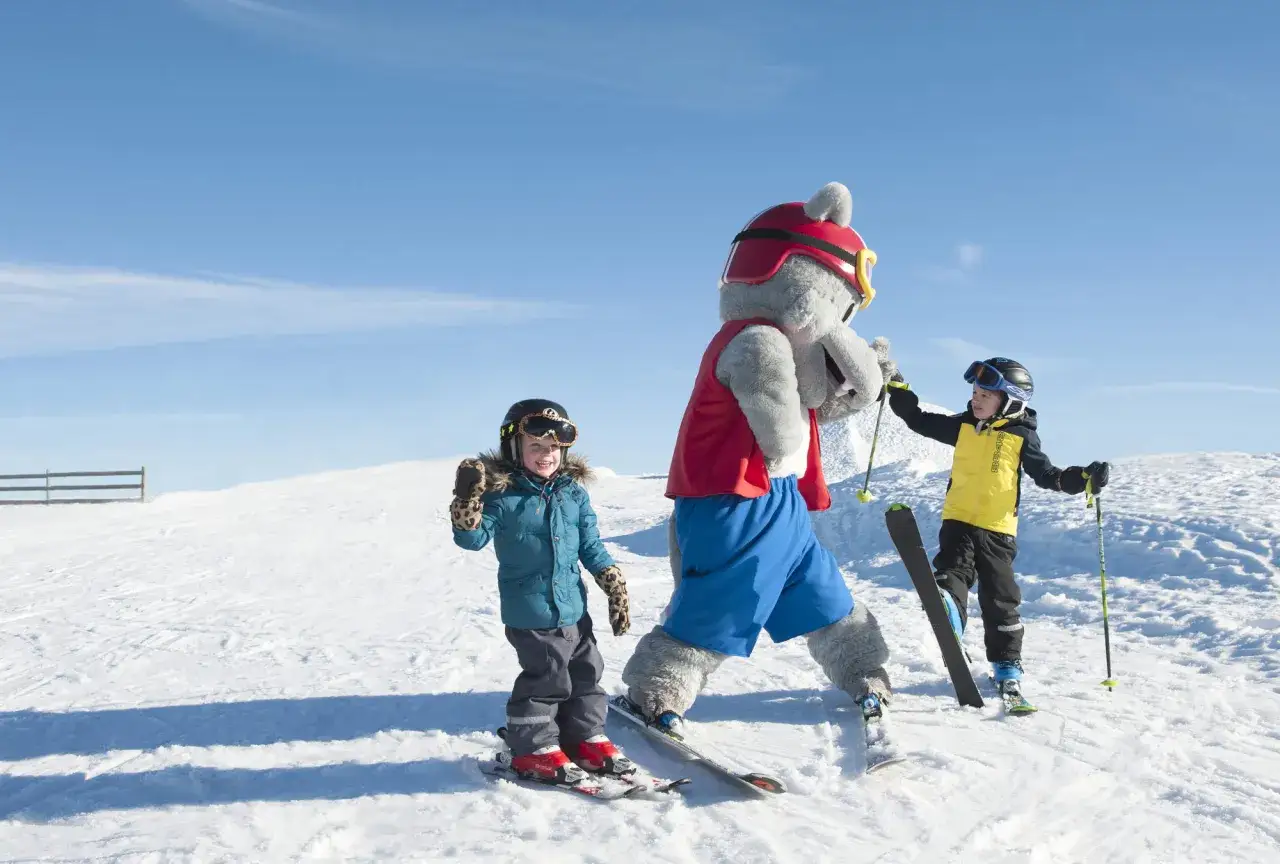 Barn på skidor med en maskot. Frågan 