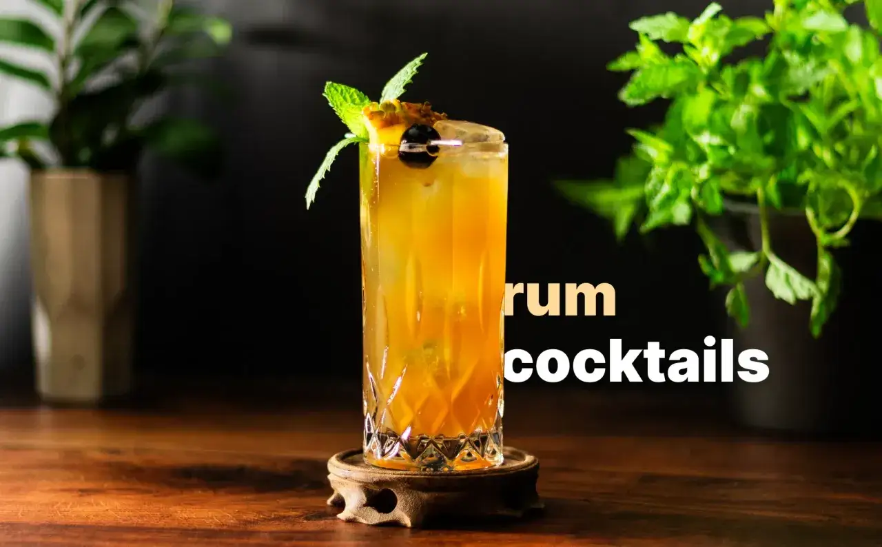 En gyllene romdrink med mynta och k&ouml;rsb&auml;r, en klassisk old cuban, st&aring;r p&aring; ett tr&auml;bord.