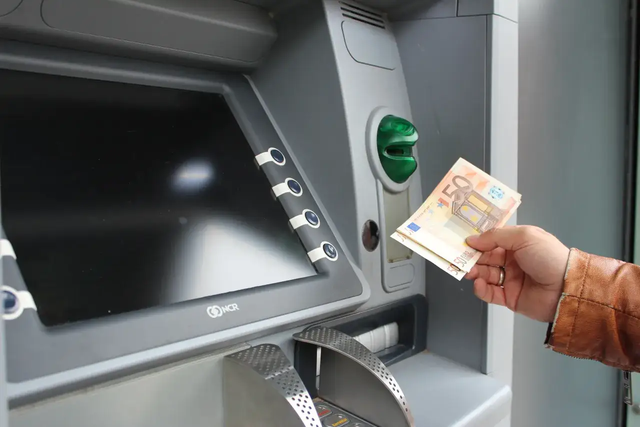 Ręka trzyma banknoty 50 euro przy bankomacie. Tak, w Grecji jest euro.