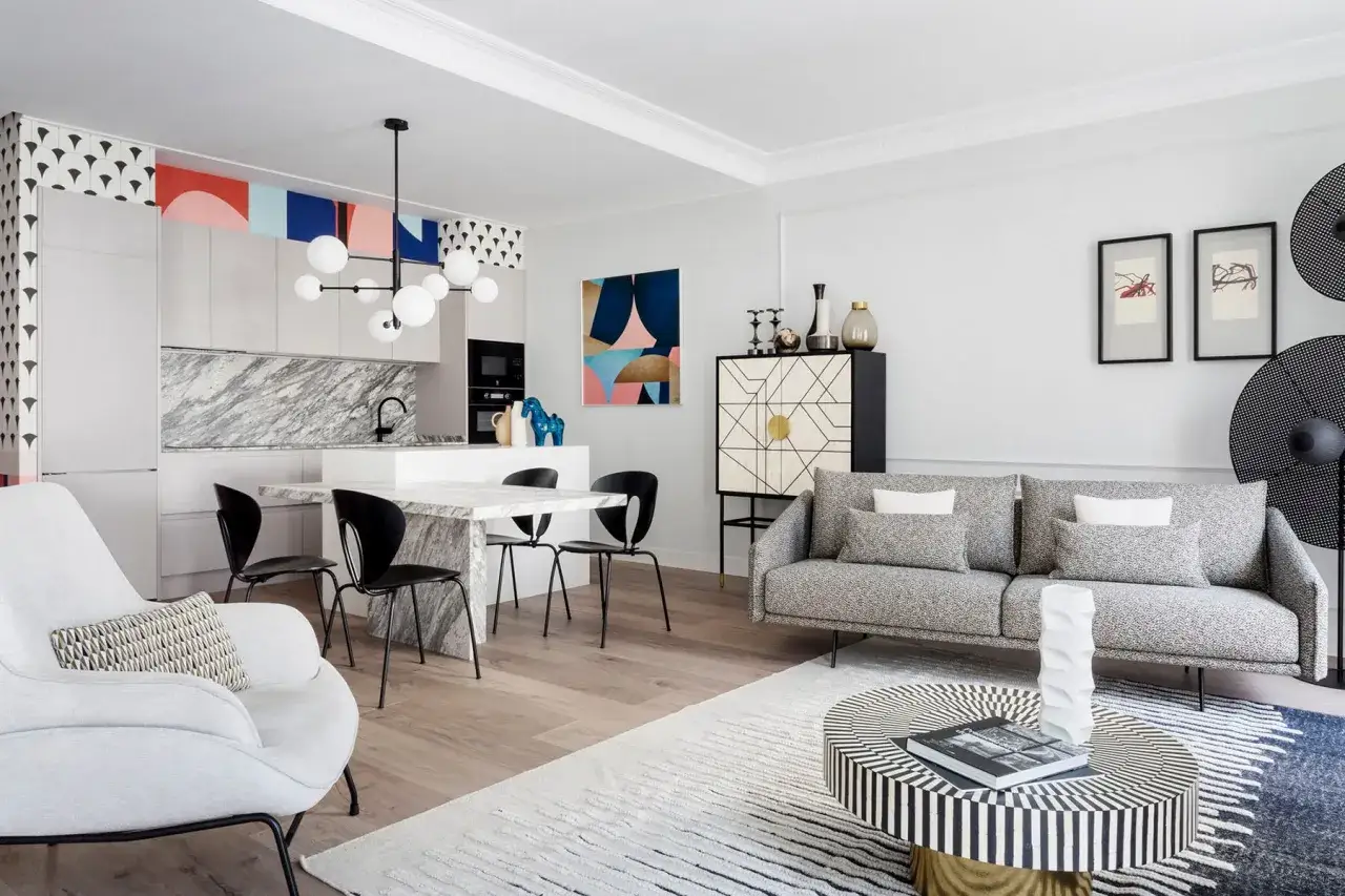 Distribución comedor moderno con cocina integrada, sofá gris, mesa de mármol y sillas negras.