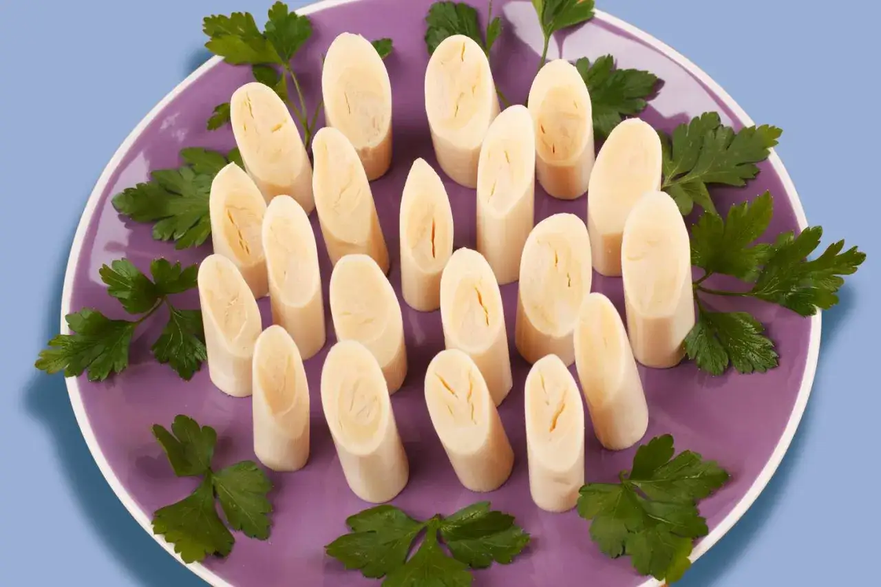 Palmito que es un manjar delicado, cortado en trozos y servido en un plato morado con perejil fresco.