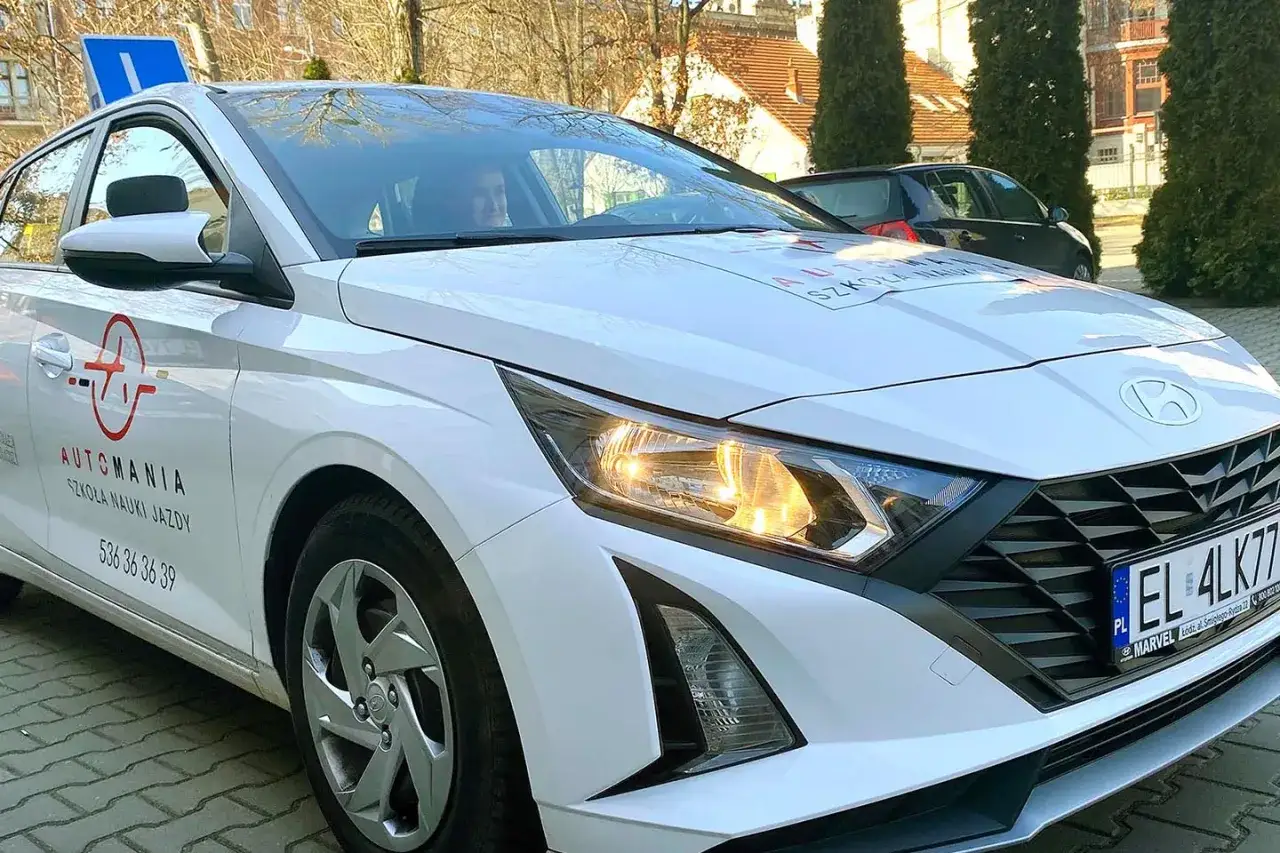 Biały Hyundai z logo szkoły jazdy 