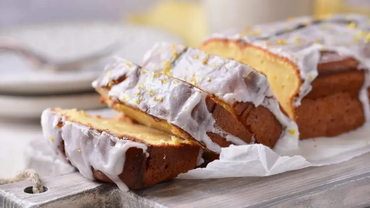 Pokrojona babka jogurtowa z lukrem i skórką cytrynową, gotowa do podania.