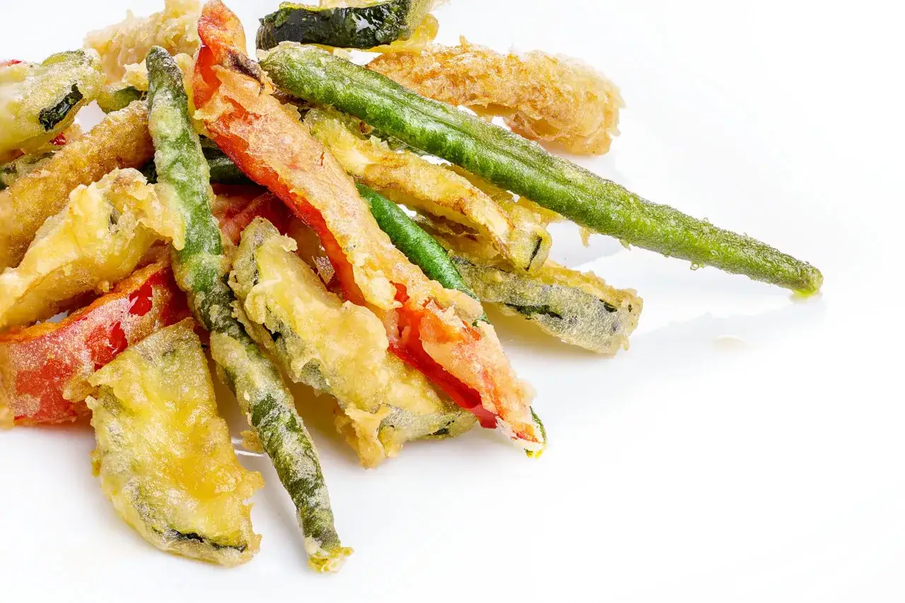 Crujiente tempura de verduras, con pimientos rojos, judías verdes y calabacín, dorados y listos para disfrutar.