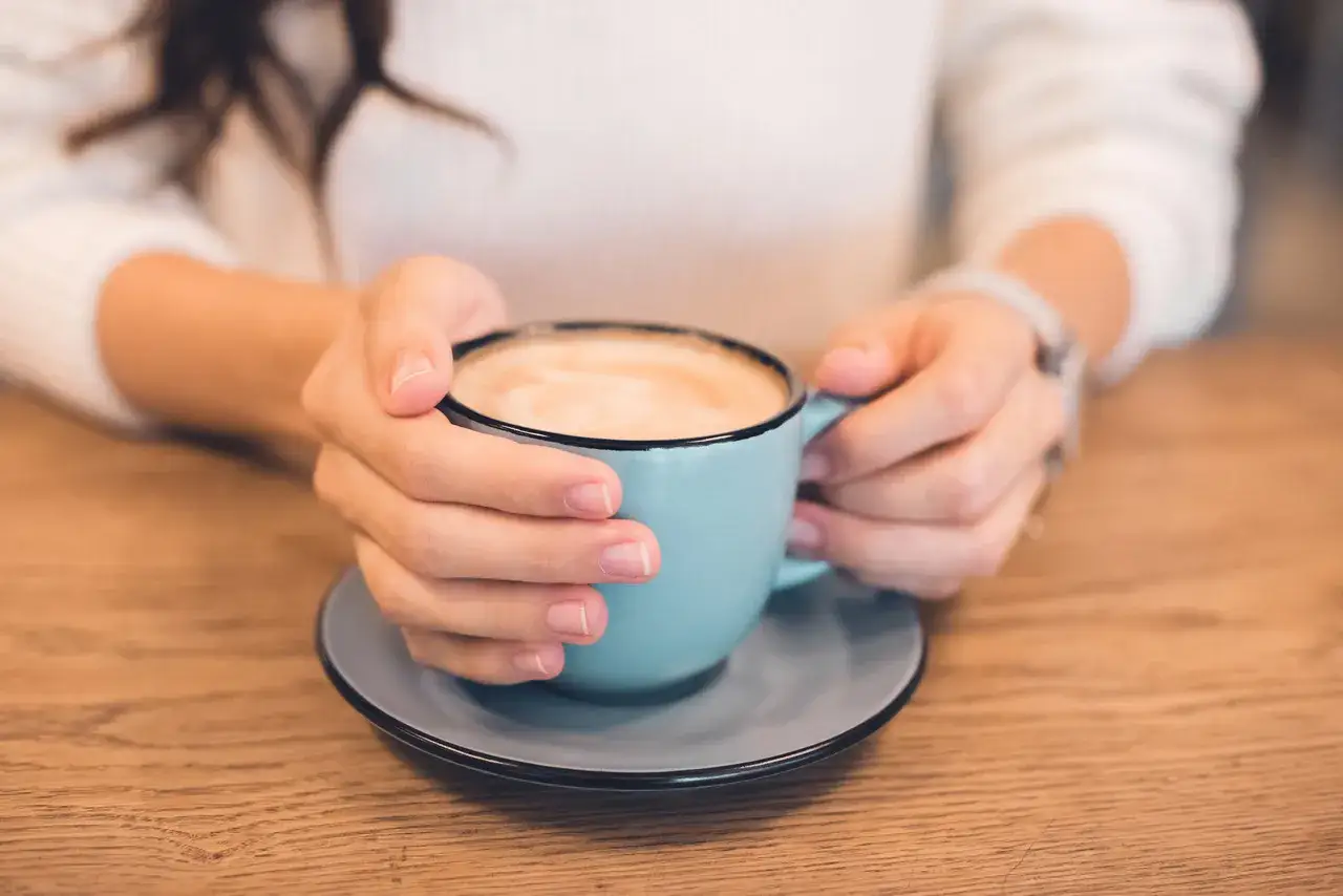 Kobieta w ciąży delektuje się kawą latte.