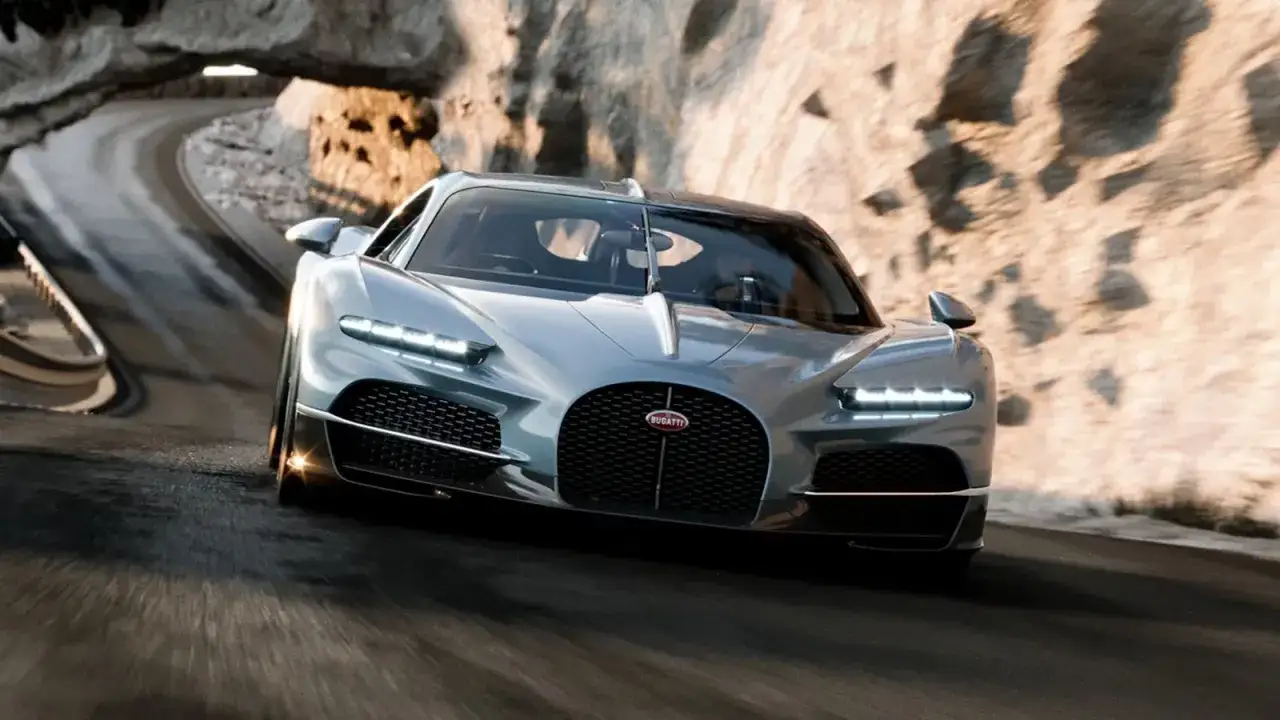 Srebrny Bugatti pędzi krętą drogą przez skalisty kanion. Taka maszyna to marzenie, a jej bugatti cena przyprawia o zawrót głowy.