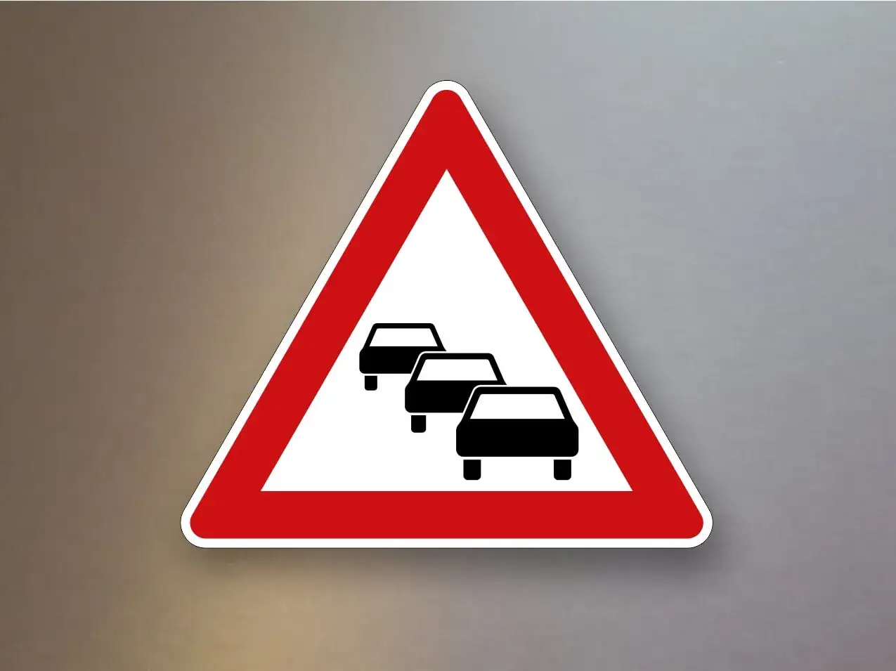 Dreieckiges Warnschild mit rotem Rand und drei schwarzen Autos hintereinander. Achtung, **stau**!