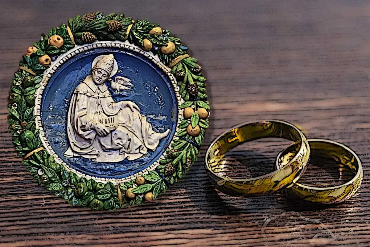 Okrągły medalion z wizerunkiem św. Grzegorza, patrona, obok dwóch złotych obrączek.