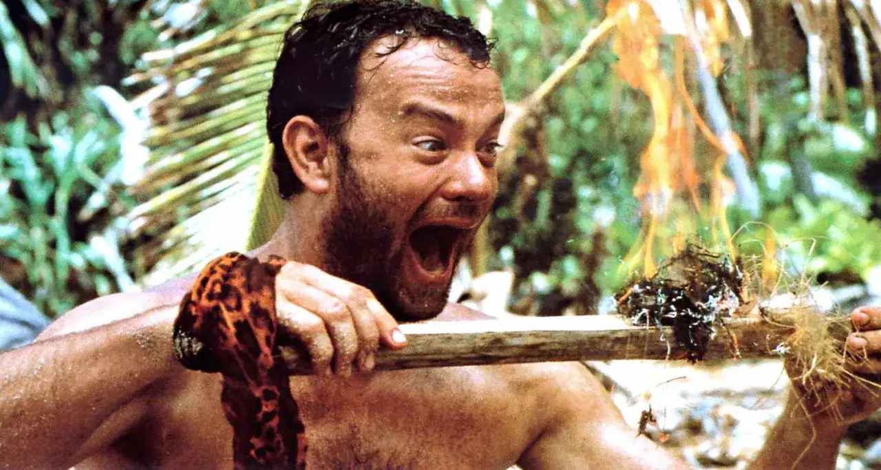 Un naufrago, con la **cast away curiosità** negli occhi, accende un fuoco su un'isola deserta.