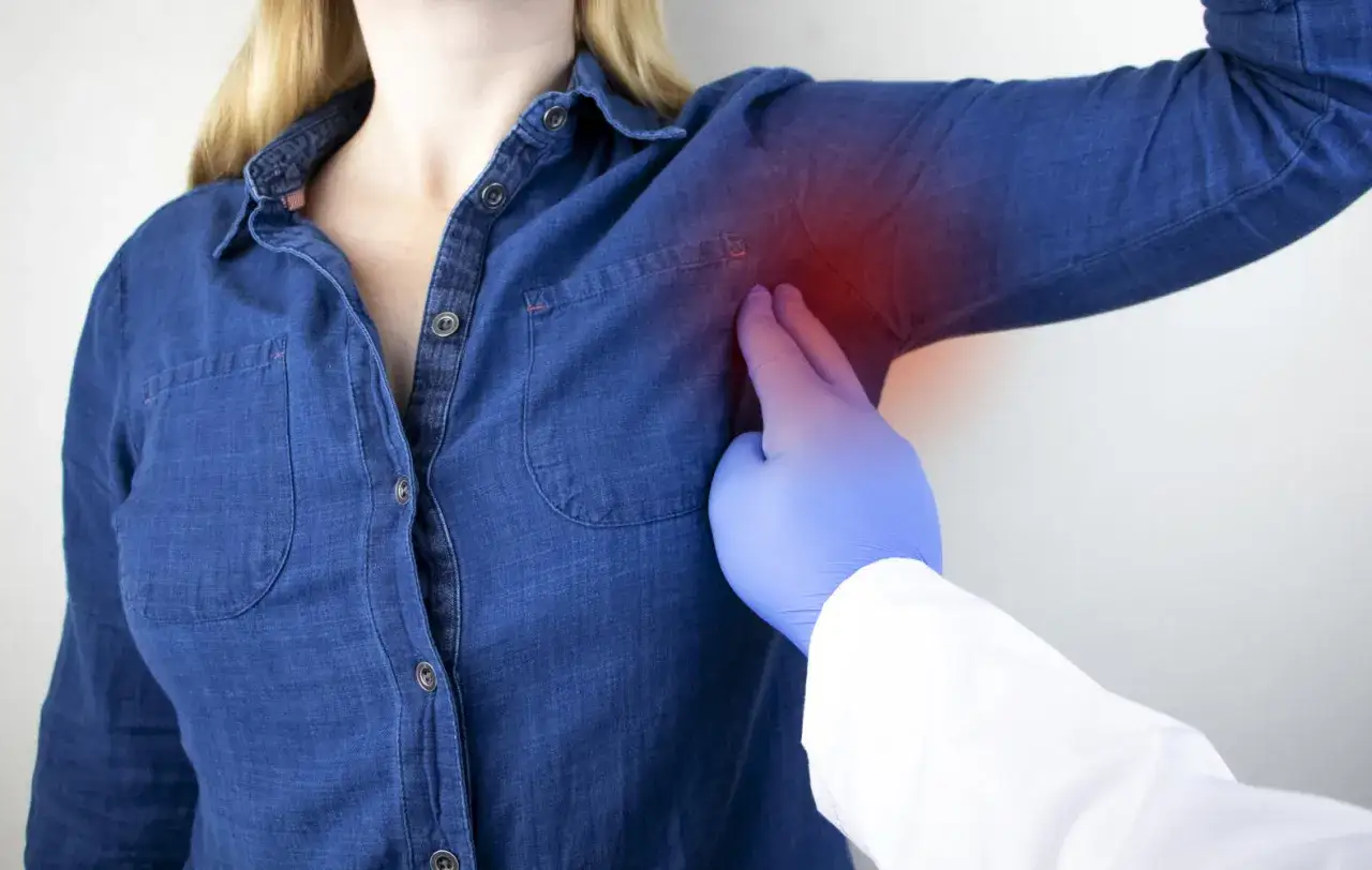 Medico esamina dolore sotto l'ascella sinistra, un sintomo che può indicare un infarto.