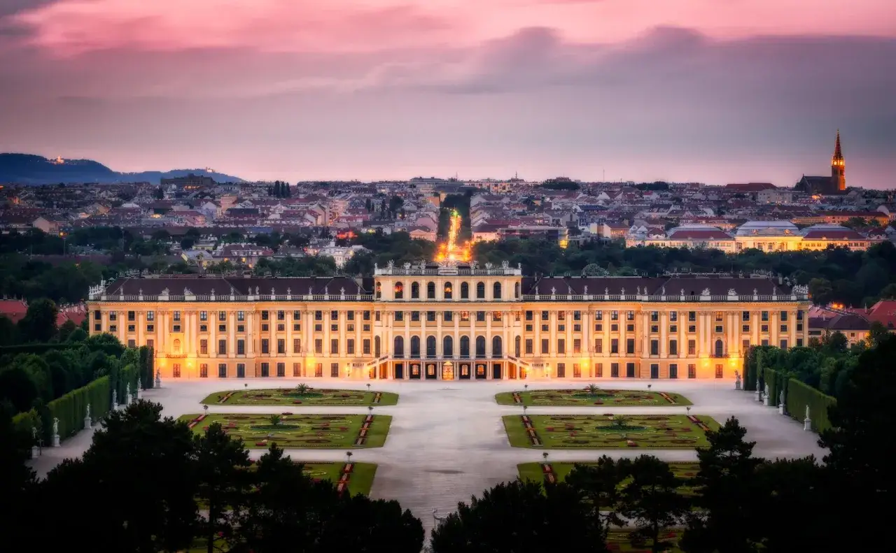 Pałac Schönbrunn o zmierzchu, z oświetlonymi fasadami i ogrodami. Warto kupić pałac Schönbrunn bilety, by zobaczyć to cudo.