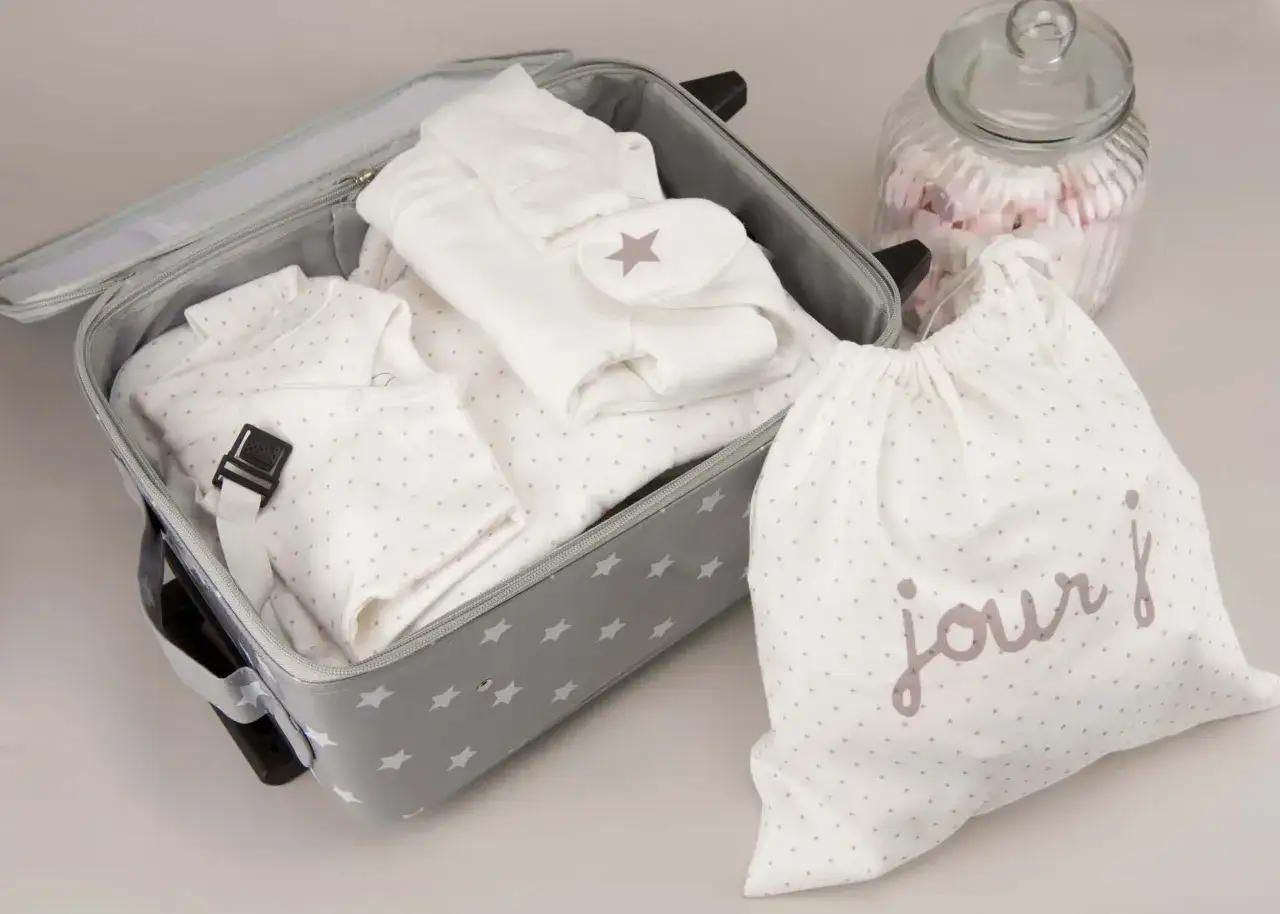 Valise grise étoilée prête pour un accouchement seule sans papa. Vêtements de bébé blancs, sac