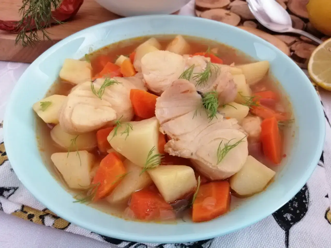 Aromatyczna zupa rybna przepis: kawałki ryby, ziemniak&oacute;w i marchewki w bulionie, udekorowana koperkiem.