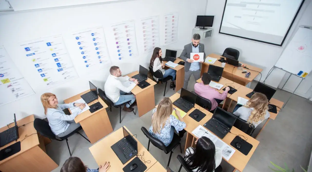 Clase de autoescuela. El profesor muestra una se&ntilde;al de STOP. Los alumnos responden a la pregunta: &iquest;cu&aacute;ntos test hay que hacer para aprobar el te&oacute;rico?