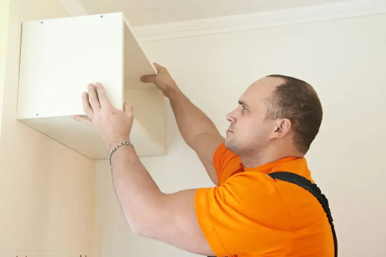 Un homme installe une &eacute;tag&egrave;re murale. Il faut bien choisir les fixations pour fixer meuble lourd sur placo.